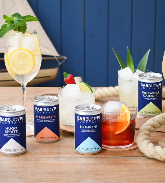 cocktail glasses and cans of cocktails with toy boat and rope