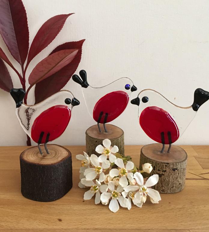 Three glass robins on stumps