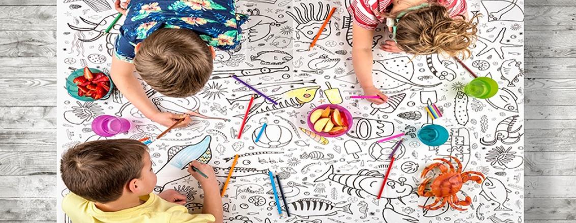 Children colouring in on a floor-sized piece of paper